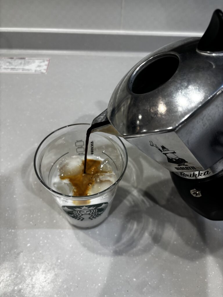 ブリッカで抽出されたコーヒーをコップに入ったミルクに注ぐ写真